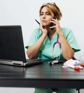 nurse on the phone at desk with laptop computer