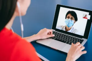 patient side telehealth with doctor in mask at desk