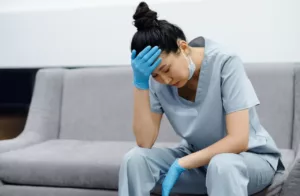 female healthcare worker tired burned out sitting mask