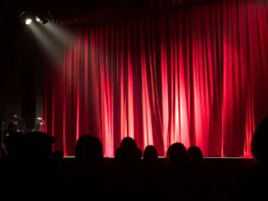 theater with crowd in the dark stage red curtains 