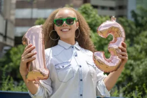 A woman holding balloons in the shape of 1 and 3