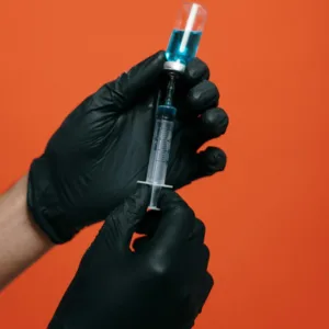 COVID-19 vaccine held by nurse red background 